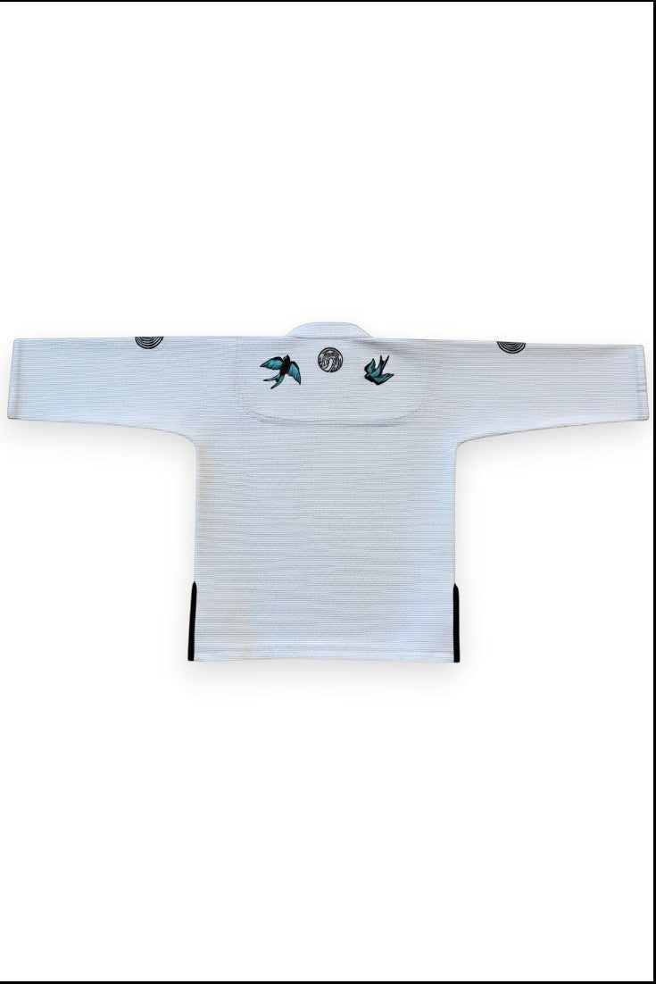 ENIGMA Kimonos white BJJ gi jacket featuring swallow embroidery on the back and reinforced cotton weave construction.