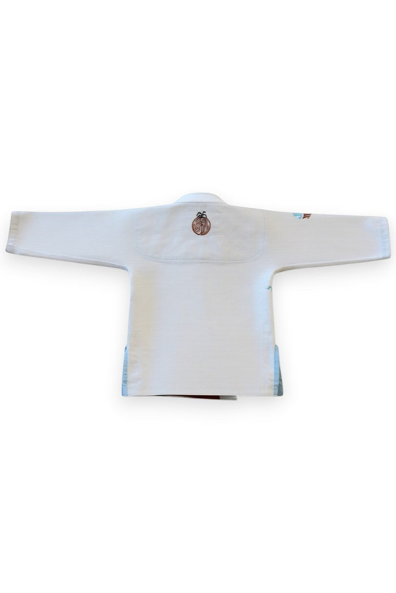 ENIGMA Kimonos white BJJ gi for kids with tropical embroidery and light blue side panels, back view.